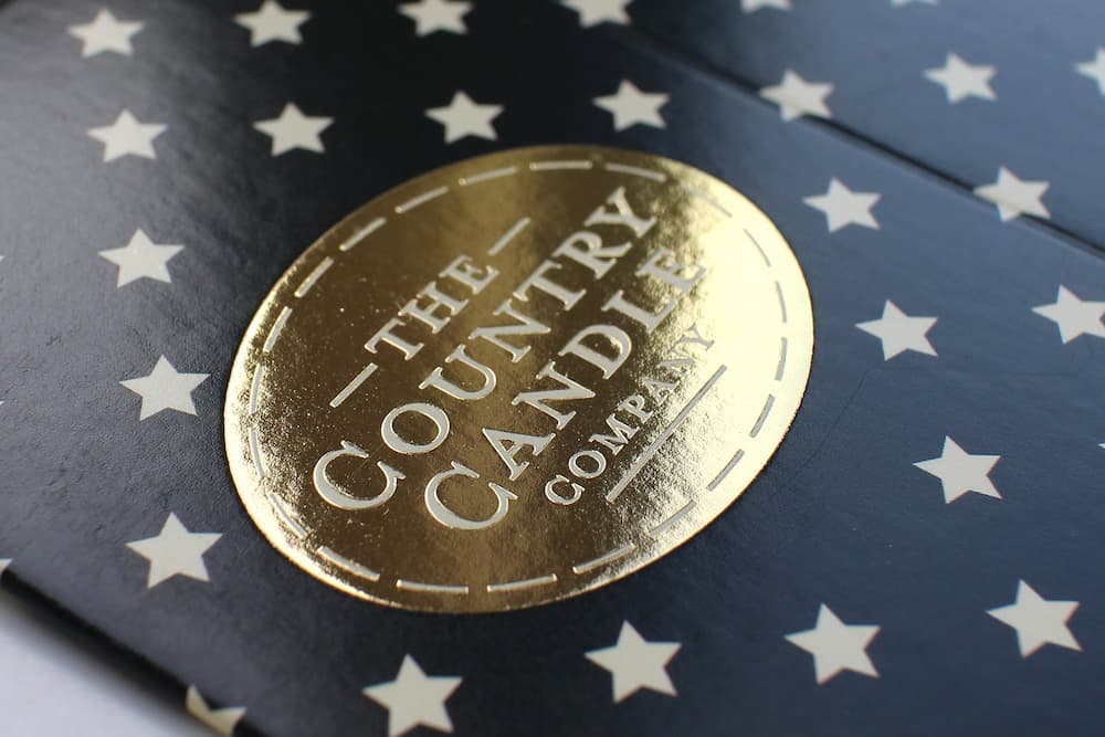 Packaging for The Candle Company with gold foil blocking on a starry navy background.